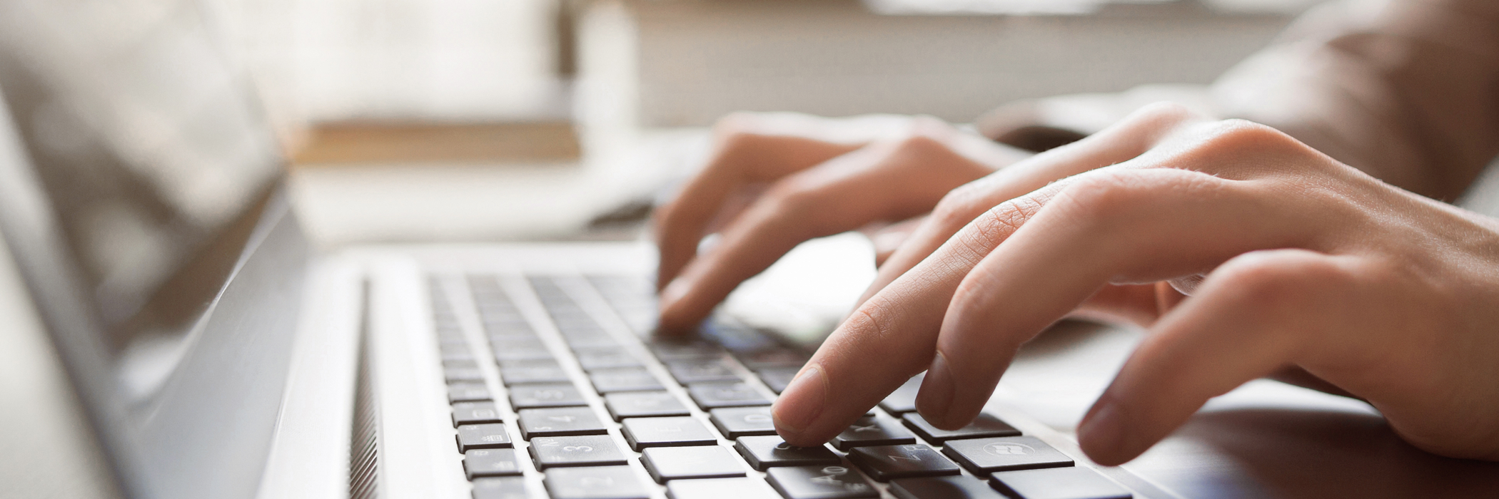Eine Person tippt auf der Tastatur eines Laptops