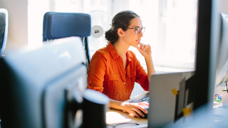 Person arbeitet konzentriert an einem Computer in einem hellen Büro
