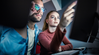 Zwei Personen arbeiten gemeinsam an einem Bildschirm